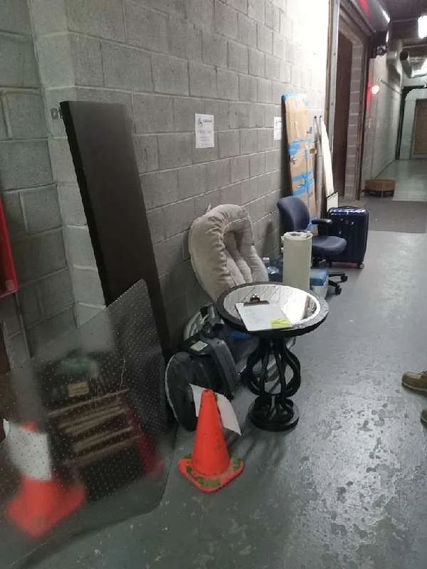 Residents' chairs, a side table, luggage and boards waiting in a back corridor on junk drive day