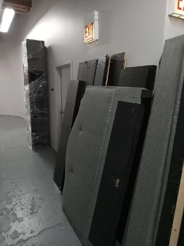 Headboards, bed frames and furniture lined up in a condo building hallway during a junk drive