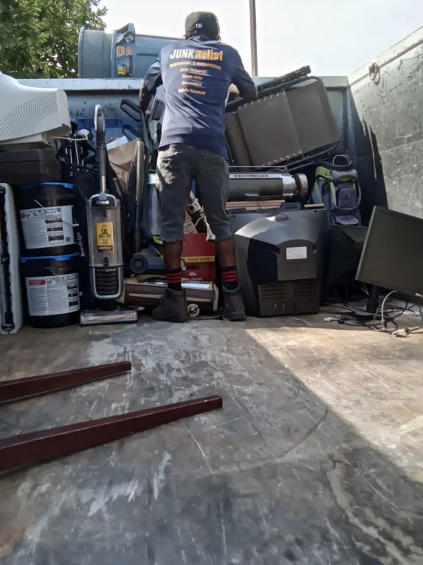 A JUNK Relief crew member stacking drop-offs inside the truck at a community junk drive
