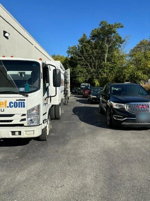Cars lined up in a real estate office parking lot, waiting to drop off items at a JUNK Relief truck
